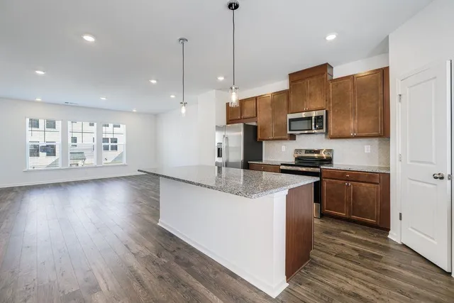 a kitchen with stainless steel appliances granite countertop a sink a stove a refrigerator and a microwave