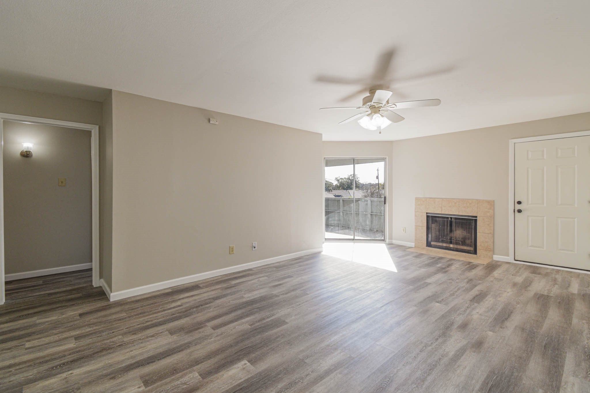 8787 Brae Acres Road, Unit 814 Houston, TX 77074 - Photo 2 of 23 an empty room with wooden floor a ceiling fan a fireplace and windows