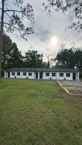 a view of a house next to a big yard with large trees