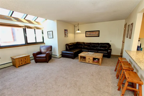 a living room with furniture and a dresser next to a window