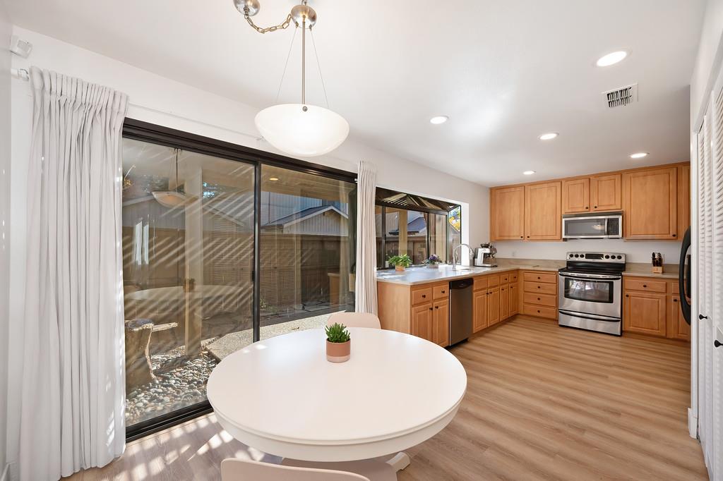 224 East Ranch Road Sacramento, CA 95825 - Photo 41 of 65 a kitchen with stainless steel appliances kitchen island granite countertop a sink a stove a dining table and chairs with wooden floor