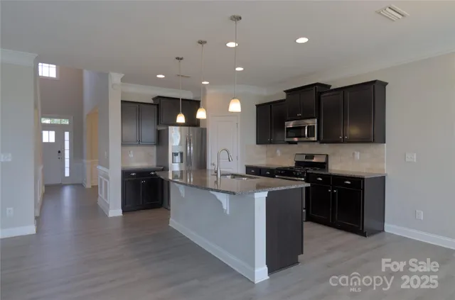 a kitchen with stainless steel appliances kitchen island granite countertop a stove a sink a refrigerator and a microwave