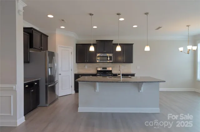 a kitchen with stainless steel appliances granite countertop a sink a stove and a refrigerator