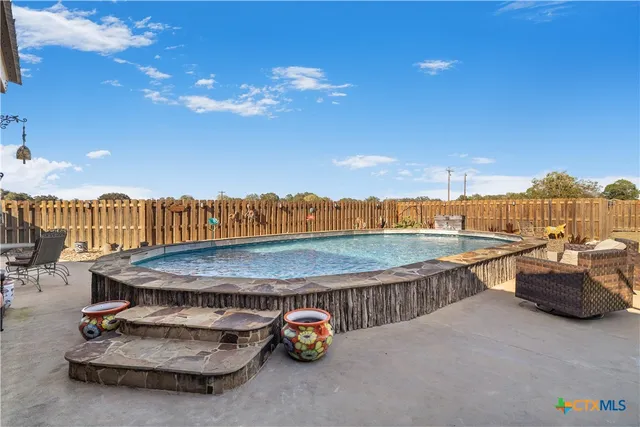 a swimming pool with outdoor seating and outdoor kitchen