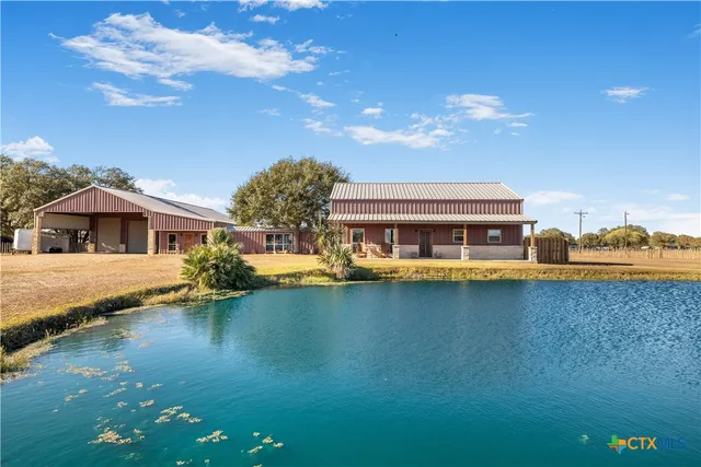 a front view of a house with a garden and lake view