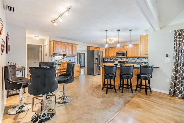 a view of kitchen with stainless steel appliances kitchen island granite countertop dining table chair and a granite counter tops