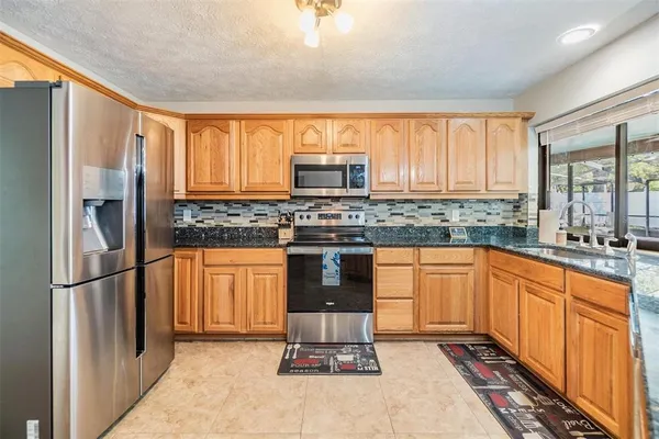 a kitchen with stainless steel appliances granite countertop a stove a sink and a refrigerator