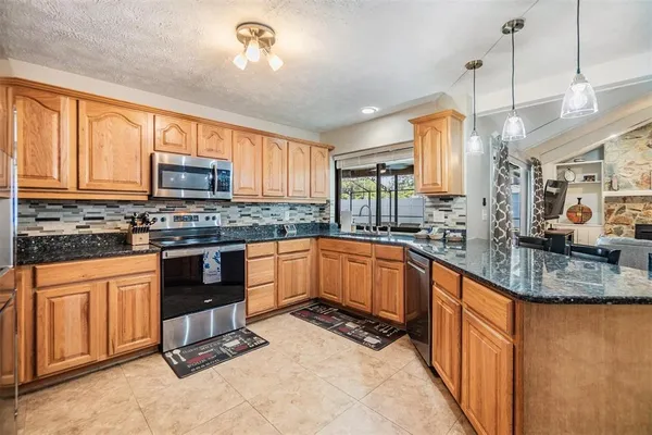 a kitchen with stainless steel appliances granite countertop a stove top oven a sink dishwasher a dining table and chairs with wooden floor