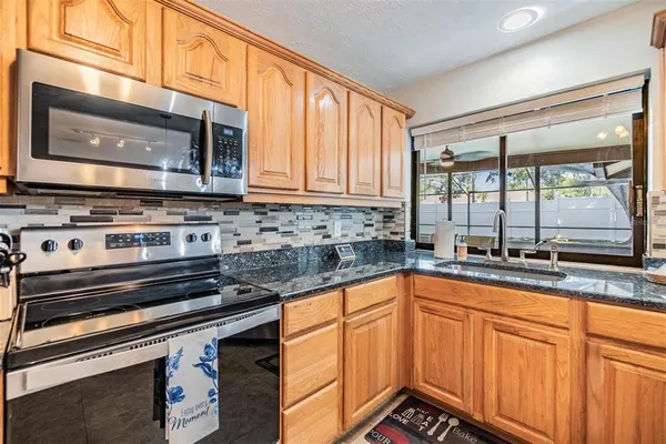 a kitchen with granite countertop a sink stove and microwave