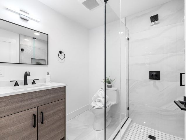 a bathroom with a granite countertop sink a toilet and a shower