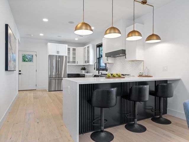 a kitchen with stainless steel appliances granite countertop a sink a stove a refrigerator and island with wooden floor