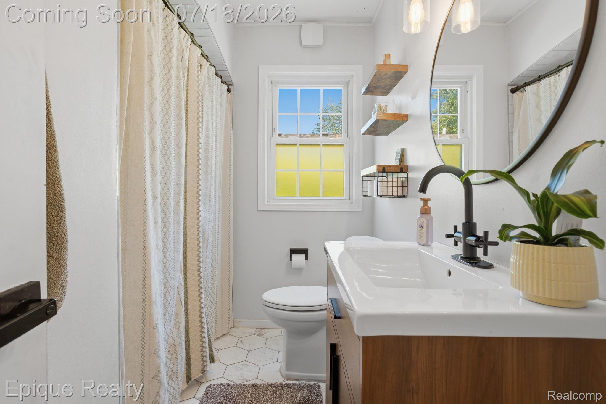1206 Hawthorne Road Grosse Pointe, MI 48236 - Photo 8 of 28 Bathroom featuring a wood-finish vanity with an integrated white sink, matte black faucet, and a round mirror