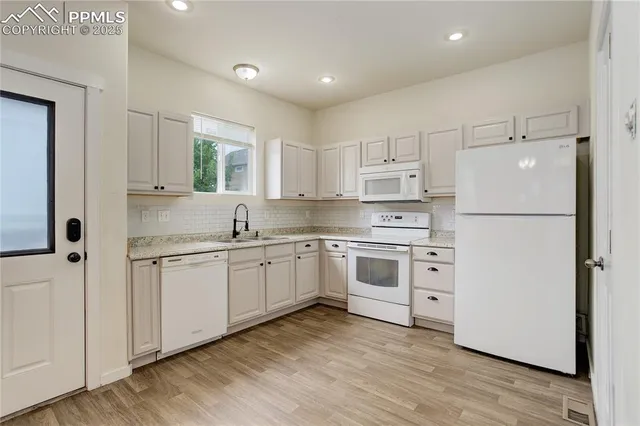 a kitchen with granite countertop white cabinets and white appliances