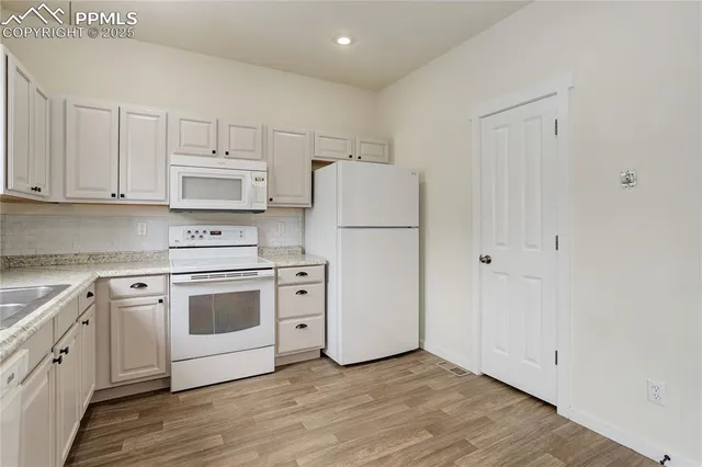 a kitchen with cabinets appliances and wooden floor