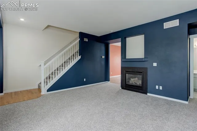 a view of an empty room with wooden floor fireplace and a window