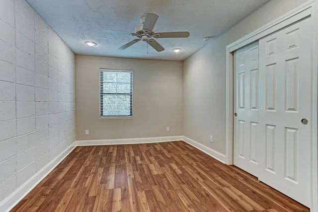 a view of empty room with wooden floor and fan