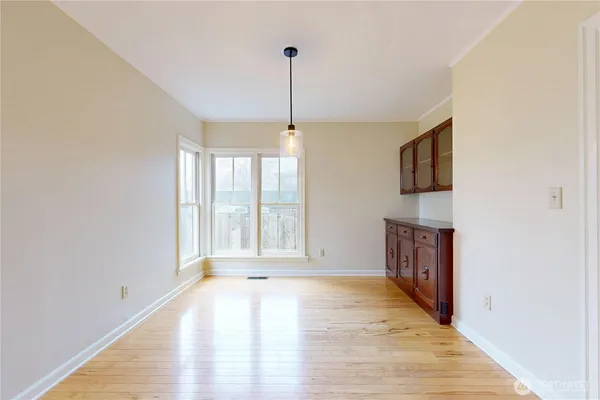 a view of an empty room with a window and wooden floor