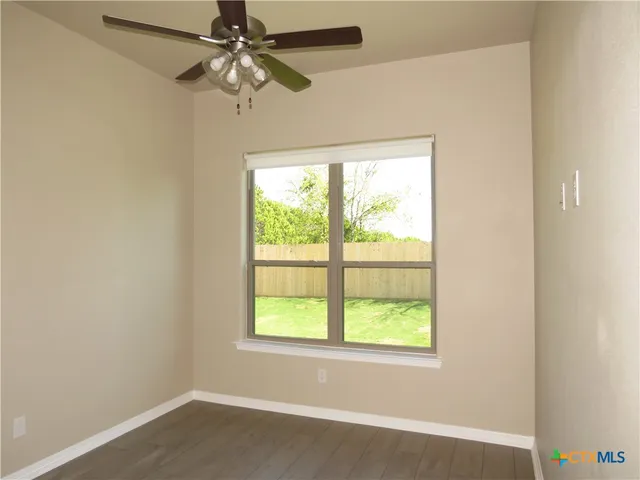 an empty room with a window and a fan