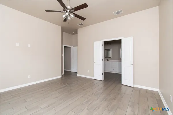 an empty room with wooden floor and a ceiling fan