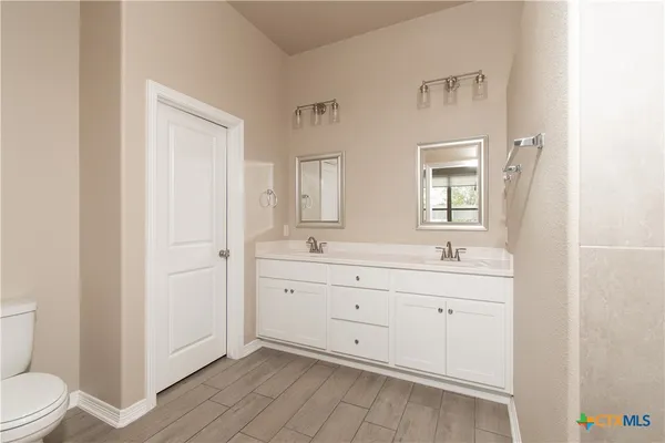 a spacious bathroom with 2 sink toilet and a mirror