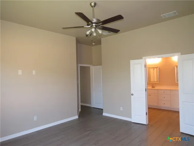 an empty room with wooden floor and a ceiling fan