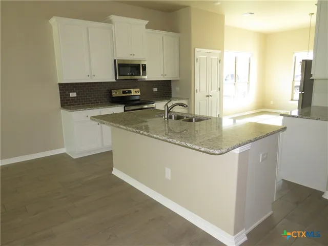 a kitchen with stainless steel appliances granite countertop a sink a stove and a refrigerator