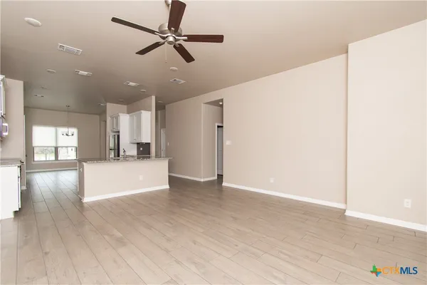 a view of an empty room with window and wooden floor