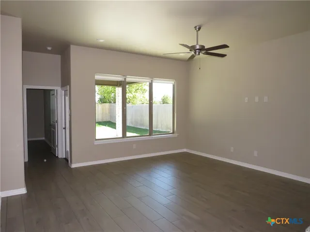an empty room with wooden floor closet and windows