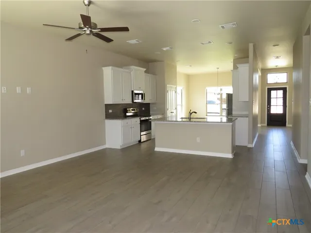 a view of a kitchen with a sink a refrigerator and wooden floor