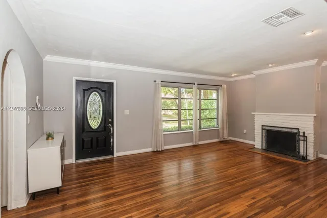 an empty room with wooden floor a fireplace and windows