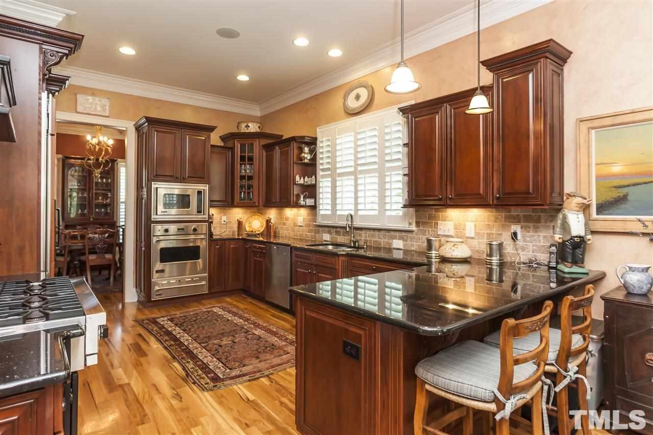 2933 Claremont Road Raleigh, NC 27608 - Photo 11 of 25 a kitchen with stainless steel appliances granite countertop a stove top oven a sink dishwasher a dining table and chairs with wooden floor