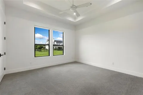 an empty room with windows and chandelier fan