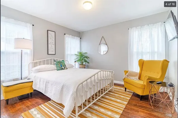 a bedroom with a bed lamp and a large window with wooden floor