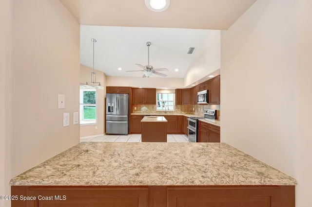 a large kitchen with granite countertop a sink a counter top space and cabinets