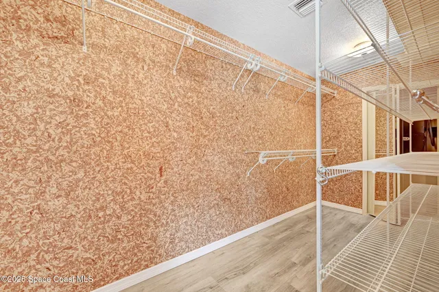 an empty room with wooden floor chandelier fan and windows