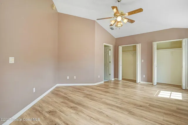 a view of an empty room with chandelier fan