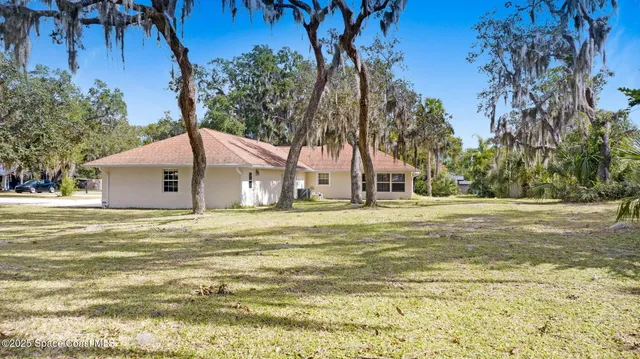 a backyard of a house with large trees and wooden fence