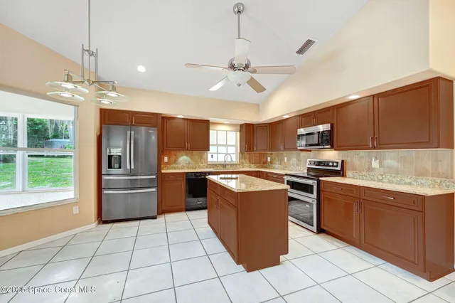 a view of an empty room with wooden floor and a kitchen