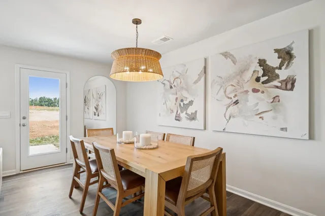 a dining room with wooden floor a chandelier a wooden table and chairs