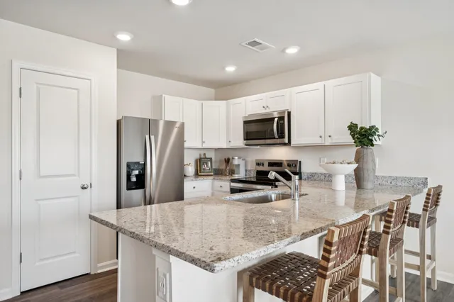 a kitchen with stainless steel appliances granite countertop a refrigerator a stove a sink a stove a dining table and chairs