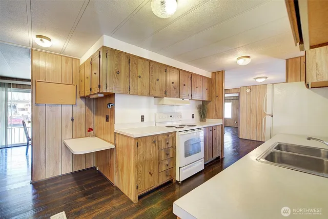 a kitchen with stainless steel appliances granite countertop a refrigerator a stove and a wooden floors