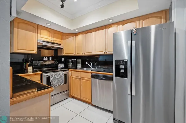 a kitchen with stainless steel appliances granite countertop a refrigerator a stove and a sink with cabinets