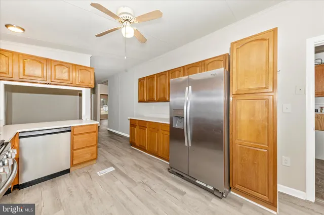 a kitchen with stainless steel appliances granite countertop a refrigerator a stove and a sink with wooden floor