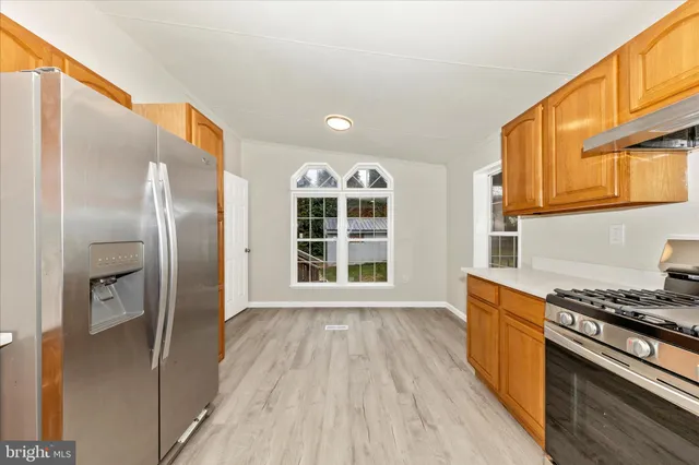 a view of a kitchen with wooden floor and stainless steel appliances