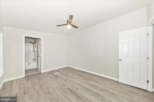 an empty room with wooden floor cabinet and ceiling fan