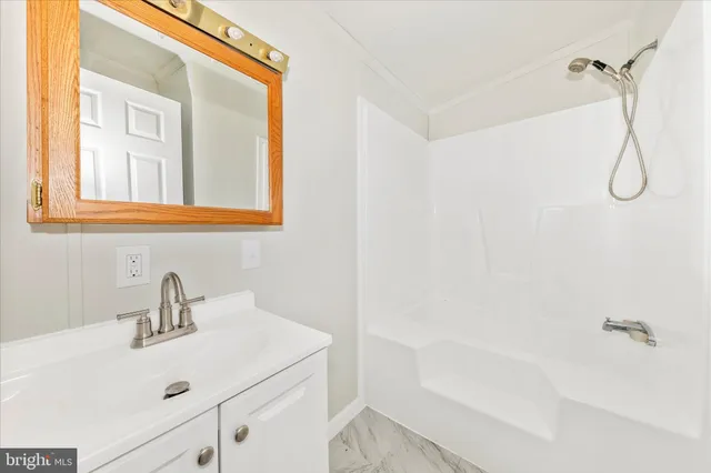 a bathroom with a sink and mirror with bathtub