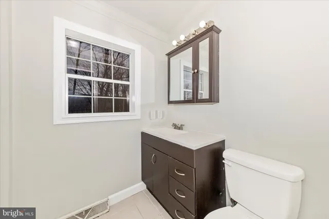 a bathroom with a toilet sink vanity and mirror