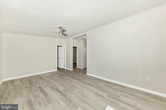 an empty room with wooden floor and ceiling fan
