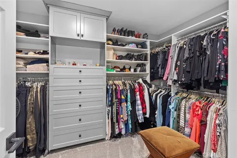a view of walk in closet with clothes and shoes