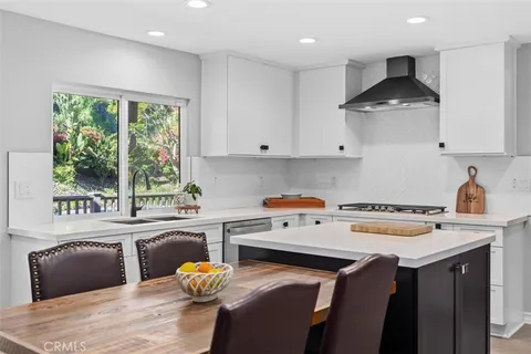 a kitchen with stainless steel appliances a stove a sink dishwasher and a refrigerator with wooden floor